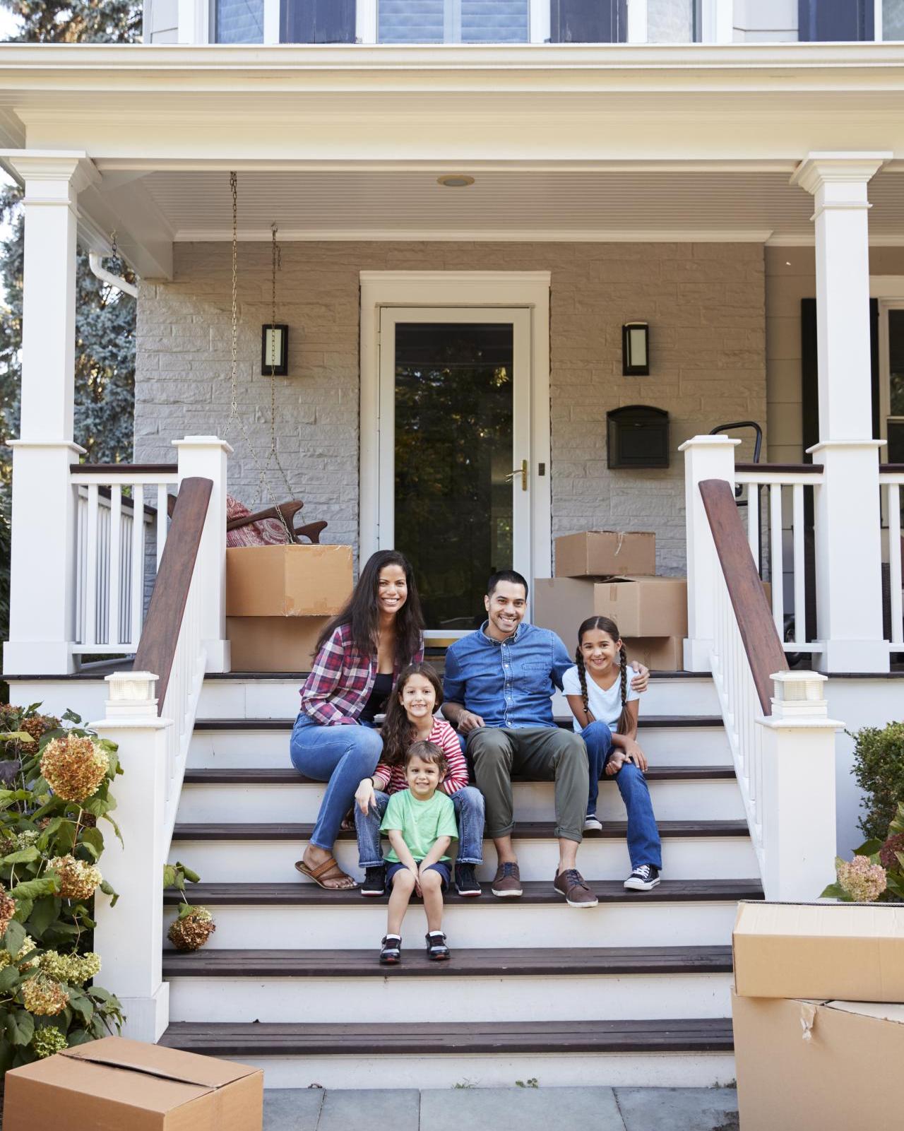 family sitting on steps of new home